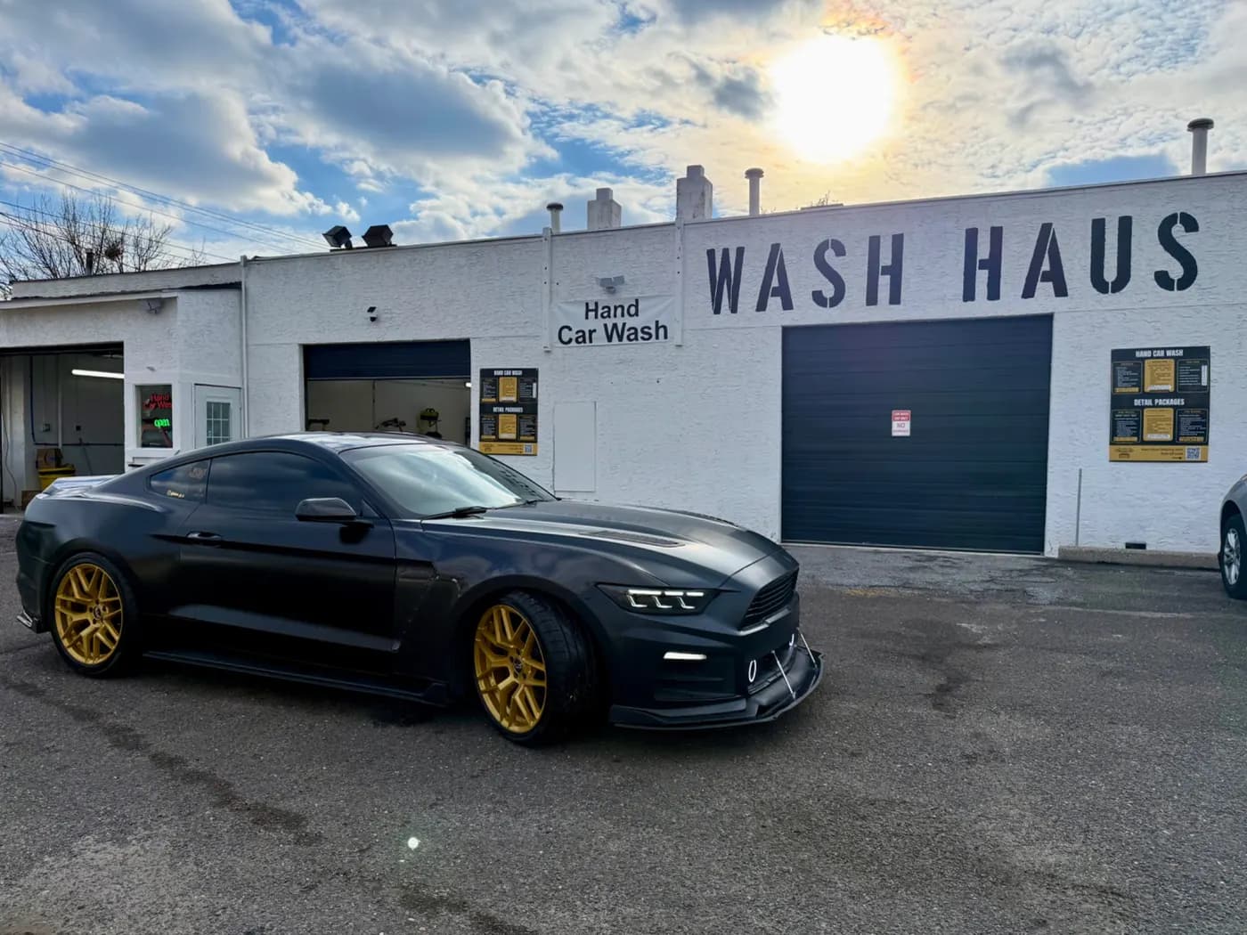 Dark Ford Mustang with gold wheels outside the Wash Haus shop
