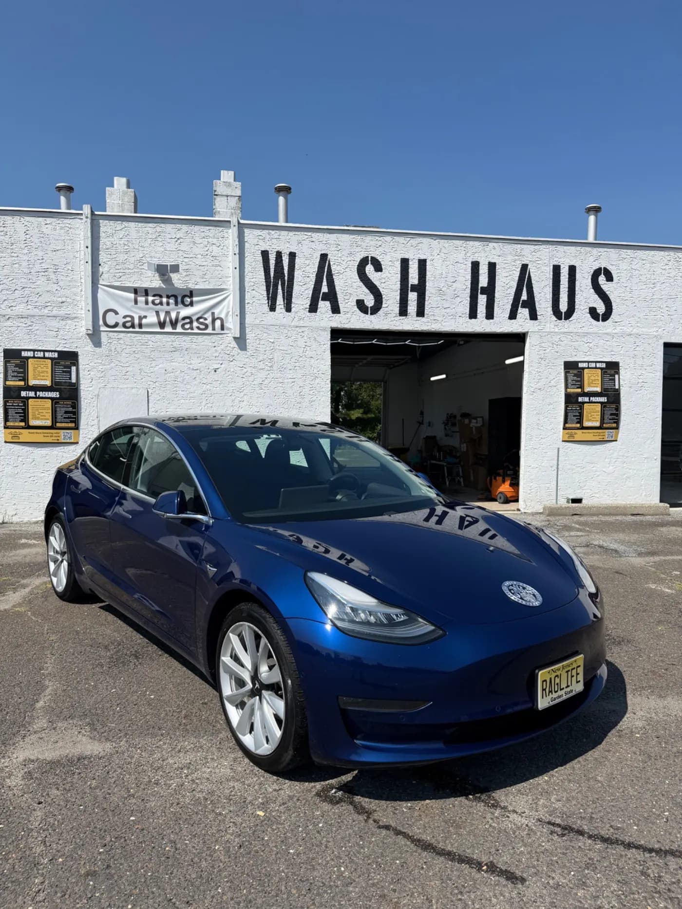 Blue Tesla Model 3 outside the Wash Haus building and sign